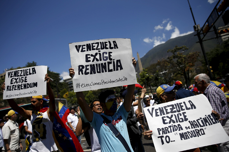 Opposition supporters hold signs during a rally against Venezuela's President Nicolas Maduro's government in Caracas, March 12, 2016. The signs read, (L-R) "Venezuela calls for referendum", "Venezuela calls for (Maduro's) resignation" and "Venezuela calls for the birth certificate of Maduro". REUTERS/Carlos Garcia Rawlins
