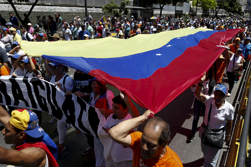 Opposition supporters carry a giant Venezuelan flag during a rally against Venezuela's President Nicolas Maduro's government in Caracas, March 12, 2016. REUTERS/Carlos Garcia Rawlins