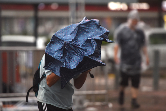 A man uses his umbrella as he walks on a street during heavy winds and rain brought on by Typhoon Hato in Hong Kong on August 23, 2017. Typhoon Hato smashed into Hong Kong on August 23 with hurricane force winds and heavy rains in the worst storm the city has seen for five years, shutting down the stock market and forcing the cancellation of hundreds of flights. / AFP PHOTO / Anthony WALLACE
