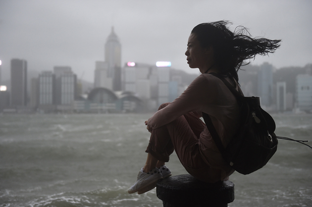 A woman looks out to Victoria Harbour during heavy winds and rain brought on by Typhoon Hato in Hong Kong on August 23, 2017. Typhoon Hato smashed into Hong Kong on August 23 with hurricane force winds and heavy rains in the worst storm the city has seen for five years, shutting down the stock market and forcing the cancellation of hundreds of flights. / AFP PHOTO / Anthony WALLACE