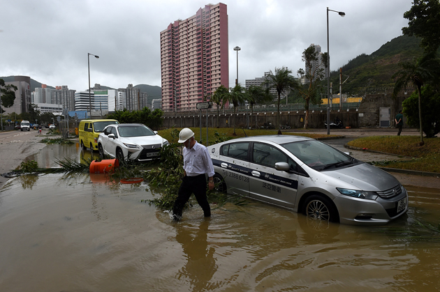 A man wades through floodwaters away from his car after heavy rains brought on by Typhoon Hato in Hong Kong on August 23, 2017. Typhoon Hato smashed into Hong Kong on August 23 with hurricane force winds and heavy rains in the worst storm the city has seen for five years, shutting down the stock market and forcing the cancellation of hundreds of flights. / AFP PHOTO / Anthony WALLACE