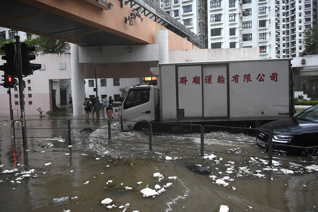 Commuters drive along a flooded road after heavy rains brought on by Typhoon Hato in Hong Kong on August 23, 2017. Typhoon Hato smashed into Hong Kong on August 23 with hurricane force winds and heavy rains in the worst storm the city has seen for five years, shutting down the stock market and forcing the cancellation of hundreds of flights. / AFP PHOTO / Anthony WALLACE