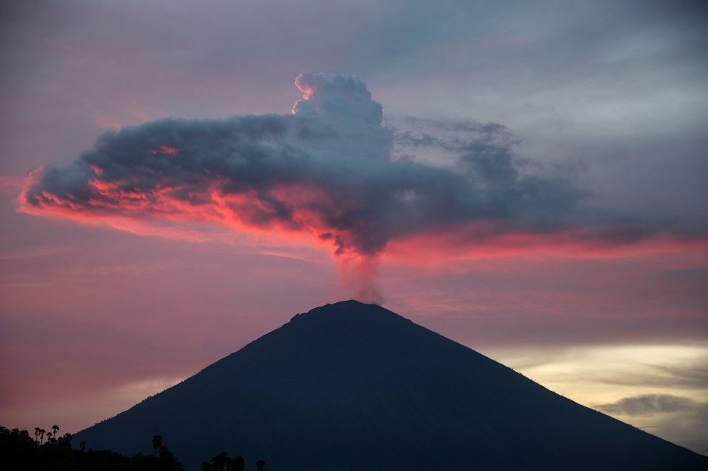 A general view shows Mount Agung from Amed beach in Karangasem on Indonesia's resort island of Bali on November 30, 2017. Thousands of foreign tourists were expected to leave Bali by plane on November 30 following a nearly three-day airport shutdown sparked by a rumbling volcano on the Indonesian holiday island. / AFP PHOTO / JUNI KRISWANTO