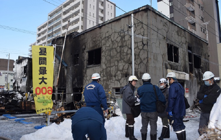Policemen and firefighters check the ruins of a fire at a residence for elderly people in Sapporo, northern Japan, on February 1, 2018. Eleven people died after a fire broke out at a residence for elderly people with financial difficulties in northern Japan, police said on February 1. / AFP PHOTO / JIJI PRESS / - / Japan OUT