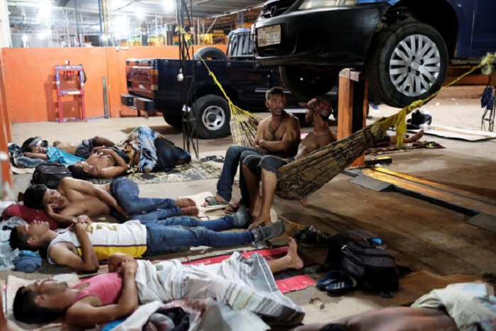 Venezuelan people are pictured on their improvised beds during the night at the car repair shop, near the interstate Bus Station in Boa Vista, Roraima state, Brazil August 25, 2018. Picture taken August 25, 2018. REUTERS/Nacho Doce