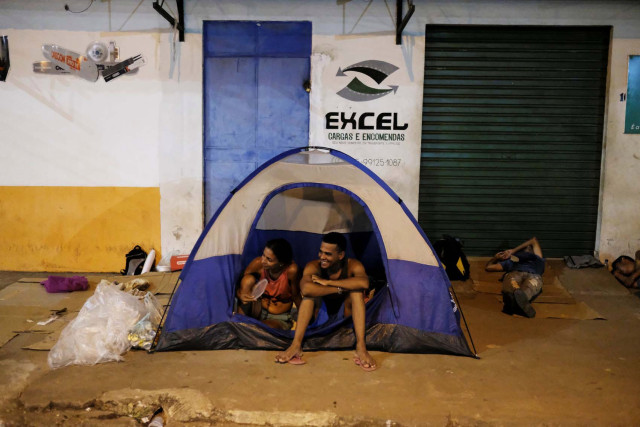 Venezuelan people sit on their tent and sleep on cardboards during the night at the entrance of packages transport shop in front of the interstate Bus Station in Boa Vista, Roraima state, Brazil August 25, 2018. Picture taken August 25, 2018. REUTERS/Nacho Doce