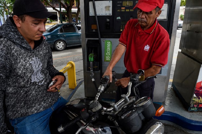 An employee pumps fuel at a gas station in Caracas, on September 20, 2018 as Venezuela tests the new gas payment system nationwide. In August, President Nicolas Maduro announced that Venezuela's dirt-cheap fuel would be available only to people with the so-called "carnet de la patria," or fatherland card, which provides access to government assistance and that the opposition had denounced as a tool for controlling people. / AFP PHOTO / Federico PARRA