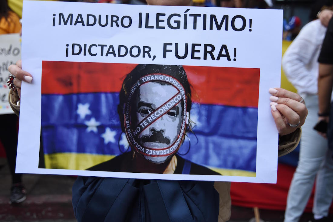 A sign reading "Maduro, illegitimate, dictator get out!" is held in a protest by Venezuelans outside their embassy in Guatemala City in support of opposition leader Juan Guaido's self-proclamation as acting president of Venezuela, on January 23, 2019. - Venezuelan opposition leader Juan Guaido declared himself interim president Wednesday, while hundreds of thousands of Venezuelans poured onto the streets to demand an end to the government of Nicolas Maduro. (Photo by Orlando  ESTRADA / AFP)