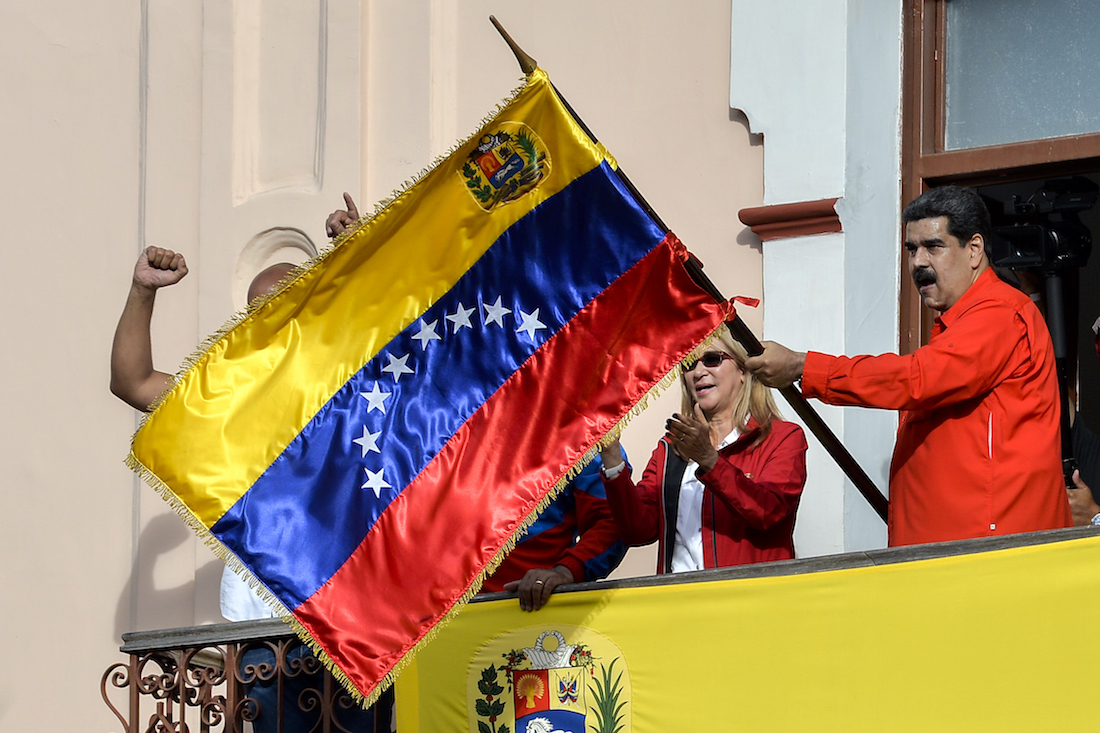 Venezuela's President Nicolas Maduro (R), flanked by his wife Cilia Flores (C), holds a Venezuelan flag while speaking from a balcony at Miraflores Presidential Palace to a crowd of supporters to announce he was breaking off diplomatic ties with the United States, during a gathering in Caracas on January 23, 2019. - Venezuela President Nicolas Maduro announced on Wednesday he was breaking off diplomatic ties with the United States after his counterpart Donald Trump acknowledged opposition leader Juan Guaido as the South American country's "interim president." (Photo by Luis ROBAYO / AFP)
