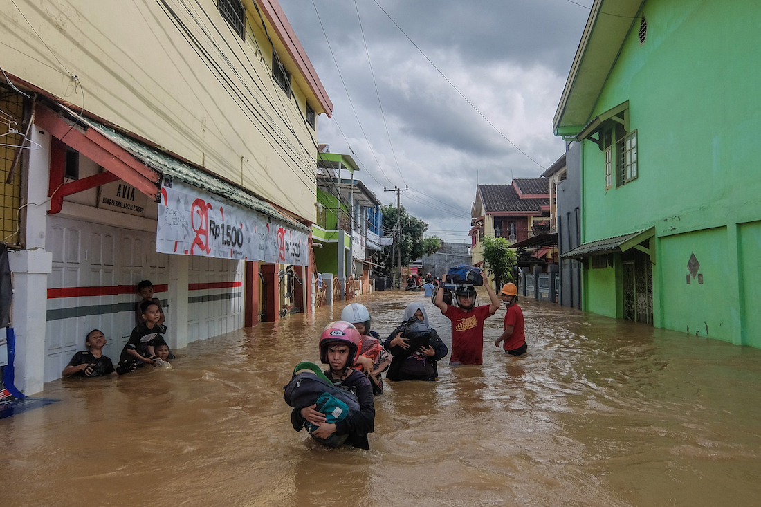 This picture taken on January 23, 2019 shows residents evacuating their homes in Makassar as heavy rain and strong winds pounded the southern part of Sulawesi island, swelling rivers that burst their banks and inundating dozens of communities in nine southern districts. - The death toll from flash floods and landslides in Indonesia jumped to 26, a disaster agency official said on January 24, as rescuers race to find still-missing victims. (Photo by STR / AFP)