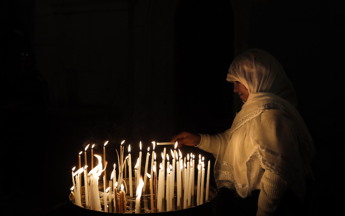 A Christian worshipper lights a candle inside the Church of the Holy Sepulchre in  Jerusalem's Old City, on January 24, 2019. (Photo by THOMAS COEX / AFP)