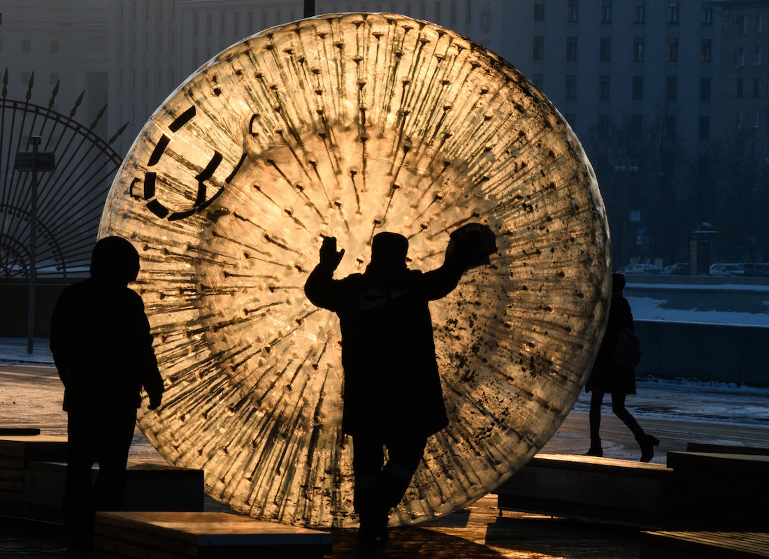 A man cleans a zorb ball outside the Gorky Park at sunset in Moscow on January 24, 2019, with the air temperatures at -16 degrees Celsius. (Photo by Mladen ANTONOV / AFP)