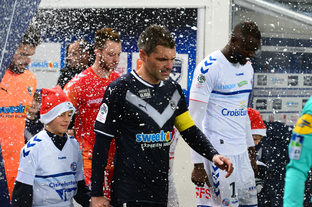 Bordeaux's French midfielder Jeremy Toulalan (C) and other players enter the pitch as false snow falls ahead of the French Ligue 1 football match between Bordeaux and Strasbourg at The Matmut Atlantique Stadium in Bordeaux, southwestern France on December 8, 2017. / AFP PHOTO / NICOLAS TUCAT