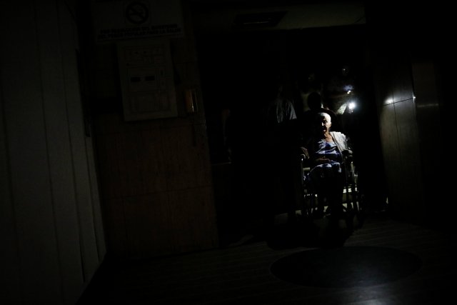 People use light from phones while they help Olimpia Mora, who is in a wheelchair, to go out from a building during a blackout in Caracas, Venezuela July 31, 2018. REUTERS/Carlos Garcia Rawlins