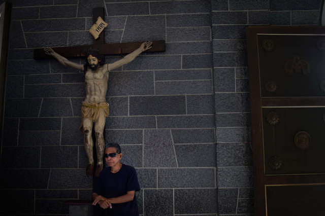 A catholic faithful attends mass at La Coromoto Church, in Caracas on August 12, 2018. The shortage of cash in the country has forced churches to accept 'plastic money' for the tithe. Demoting the Christian mandate of discretion, many faithful enter the sacristy and use their debit or credit cards, revealing their name, ID number and amount of the tithe. / AFP PHOTO / Federico PARRA