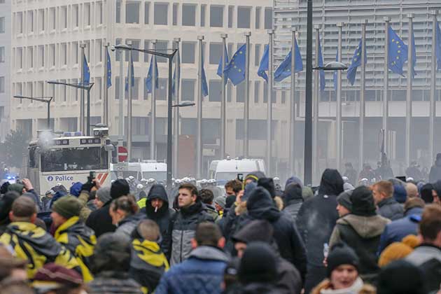 Brussels (Belgium), 16/12/2018.- Protesters of right-wing and far-right Flemish associations take part in the 'March Against Marrakech' demonstration as a police vehicle (L) with water cannons stands near European institutions headquarters in Brussels, Belgium, 16 December 2018. Anti-immigration protesters took to the streets of Brussels to denounce the Global Compact on Migration adopted in Marrakesh and approved by the Belgian Prime Minister. The march was organized by several right-wing and far-right Flemish associations such as KVHV, NSV, Schild & Vrienden, Voorpost and Vlaams Belang Jongeren. (Protestas, Bélgica, Bruselas) EFE/EPA/JULIEN WARNAND